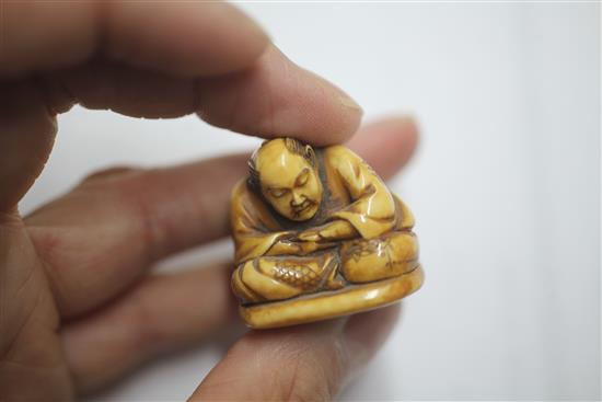 A Japanese ivory netsuke carved with nine Noh masks and another of a seated man asleep, both signed (2)